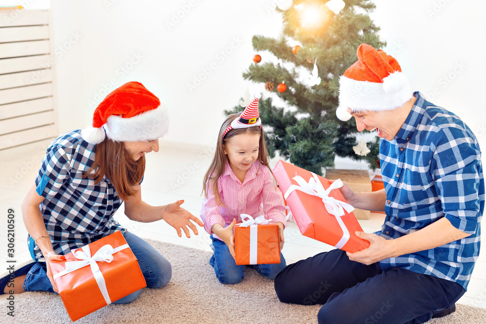 Obraz premium Holidays and presents concept - Portrait of a happy family opening gifts at Christmas time