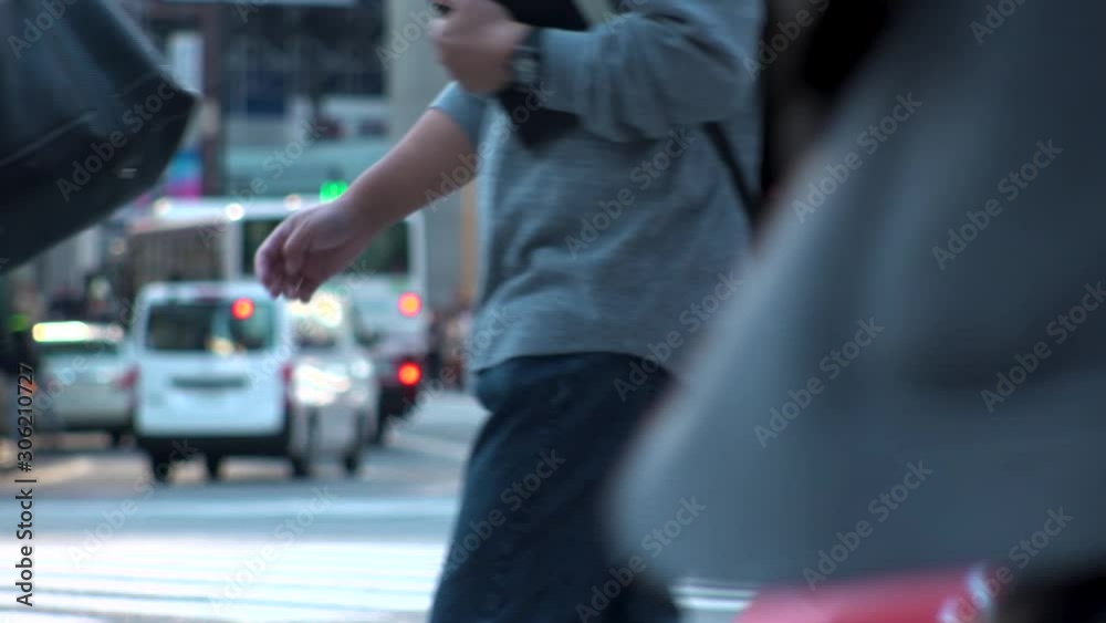 TOKYO, JAPAN - NOV 2019 : Crowd of people at Shibuya Scramble Crossing in busy early evening rush hour. Many commuters and tourists at the street. Shot in sunset time. In front focus. Slow motion. TOKYO, JAPAN - NOV 2019 : Crowd of people at Shibuya Scramble Crossing in busy early evening rush hour. Many commuters and tourists at the street. Shot in sunset time. In front focus. Slow motion.