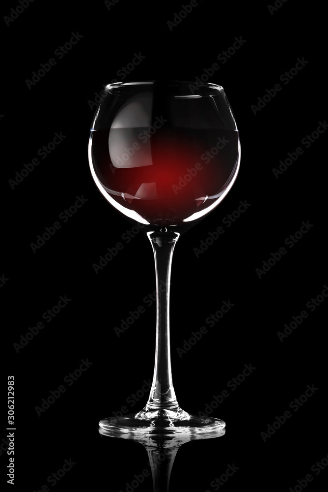 A glass of red wine on a black background in a contrasting light A glass of red wine on a black background in a contrasting light