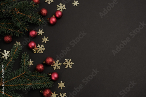Christmas winter composition. Red balls with fir branches and snowflakes on black background. Top view, flat lay