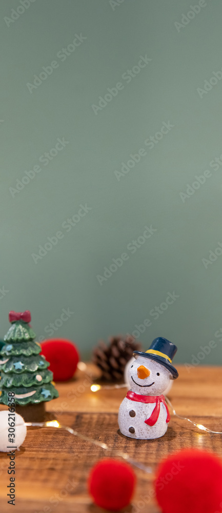 Fototapeta premium Christmas decoration (snowman, santa, gift box, pine cones, socks, lights) on green background