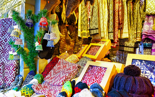 Knitted goods displayed on a Christmas market stall. Old Town of Riga, Latvia. Wool mittens, gloves, socks with hats in winter. Street Xmas and holiday fair in European city. Advent Crafts on Bazaar © Roman Babakin
