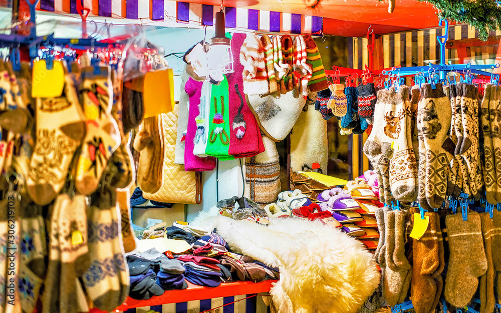Stalls at the Christmas Market in Riga, Latvia. Warm clothes. Wool mittens, gloves, socks with hats in winter. Street Xmas and holiday fair. Advent Decoration with Crafts Items on Bazaar