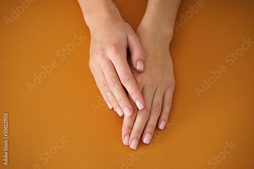 Hands of a young woman with beautiful manicure on a beige background. Female manicure. Close-up.