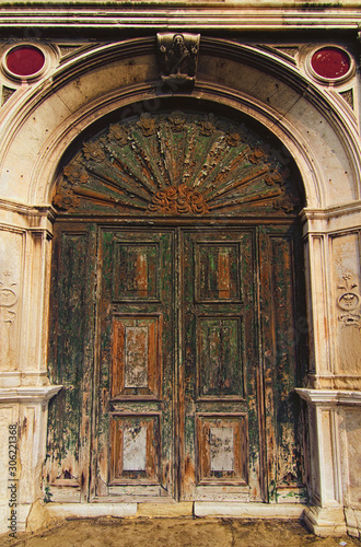 Ancient wooden door with arc in brick wall. Elements of architectural decoration of building. Venice, Italy