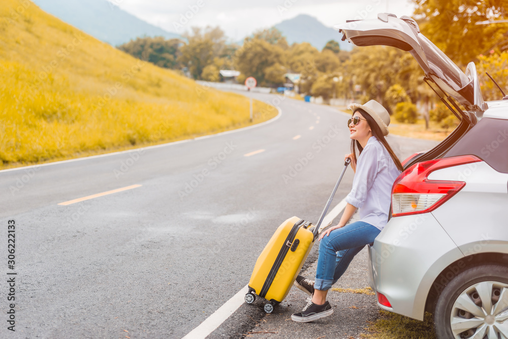 Beautiful Asian young woman wear hat and sunglasses sitting smiling on hatchback car Beautiful Asian young woman wear hat and sunglasses sitting smiling on hatchback car
