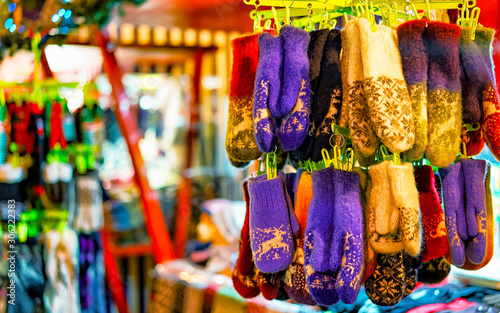 Colorful warm gloves at the Christmas Market in Riga, Latvia. Clothes. Wool mittens on stalls in winter. Street Xmas and holiday fair in European city or town. Advent Decoration with Crafts on Bazaar © Roman Babakin
