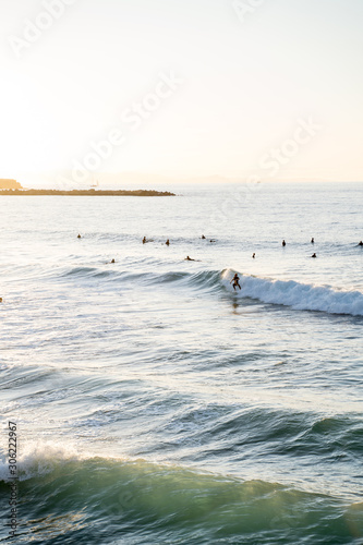 Surfers riding waves on Zurriola Beach in San Sebastian during sunset