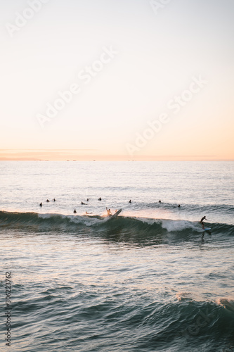 Surfers riding waves on Zurriola Beach in San Sebastian during sunset