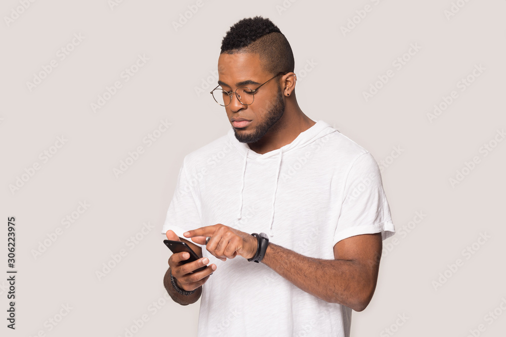 Serious African American man using phone, looking at screen