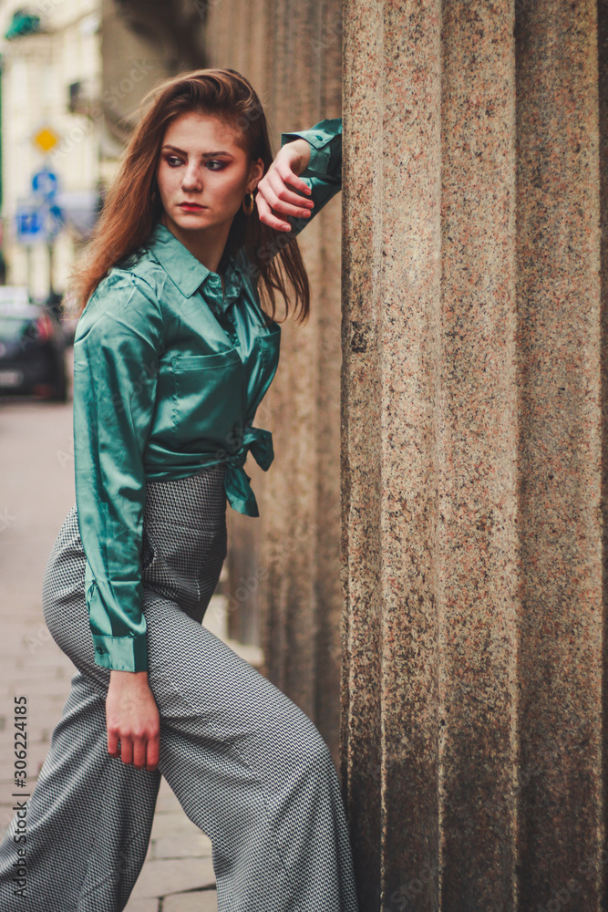 Obraz premium Fashion shooting. Wide trousers tube. Satin emerald blouse. Fashion trend. Tall brunette model.