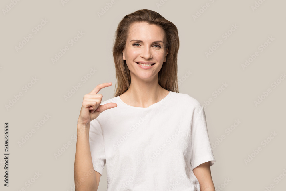 Smiling young woman showing little size gesture with fingers Smiling young woman showing little size gesture with fingers