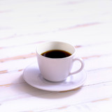 cup of black coffee on a white background. coffee on a white wooden background. espresso in a white cup. coffee in a white cup on a white wooden background