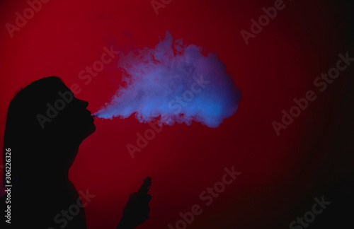 Girl silhuette smoking vape on a red background photo