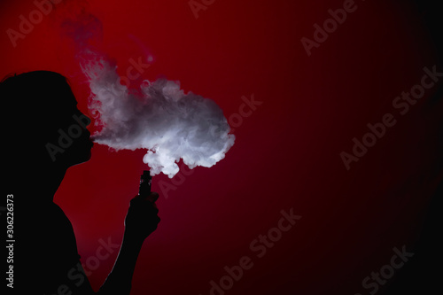 Girl silhuette smoking vape on a red background
