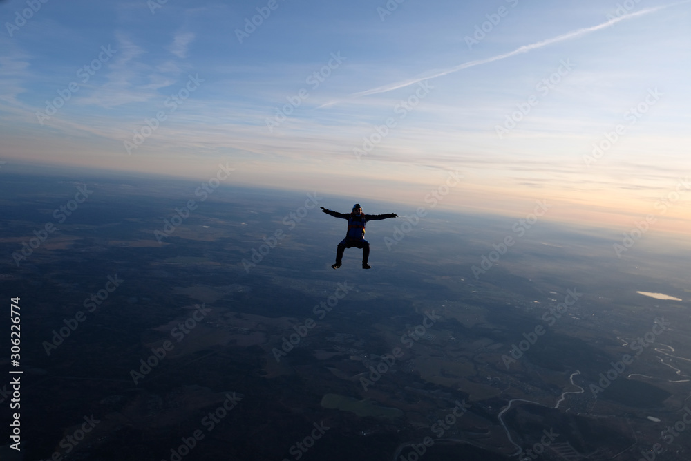 Skydiving. A solo skydiver is in the sunset sky.