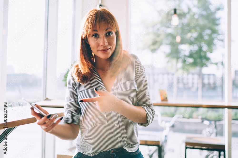 Portrait of surprised female blogger shocked with received advertising email on modern cellphone device, amazed red hair woman pointing on smartphone gadget during online shopping wonder with discount Portrait of surprised female blogger shocked with received advertising email on modern cellphone device, amazed red hair woman pointing on smartphone gadget during online shopping wonder with discount