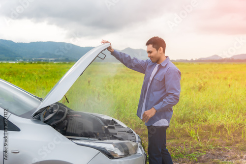Asian young man having trouble car engine overheating and have smoke