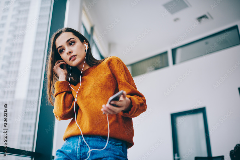 Pondering caucasian hipster girl dressed in casual look using wireless 4g  connection for listening radio online via smartphone application,  thoughtful woman in electronic headphones enjoying song Stock Photo | Adobe  Stock