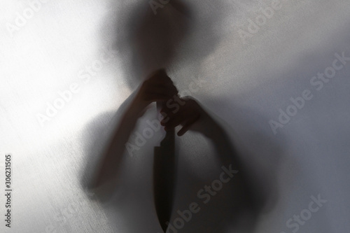 no focus. the fabric behind her. silhouette and shadow. the child has a knife in his hands. domestic violence concept. photo