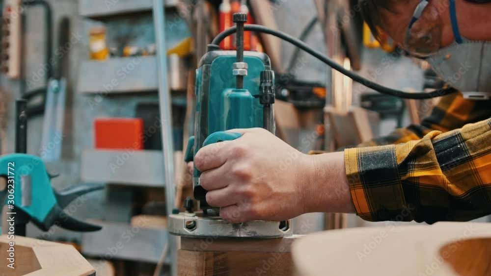 Carpentry industry - a woodworker polishes the side of the wooden detail in a workshop Carpentry industry - a woodworker polishes the side of the wooden detail in a workshop