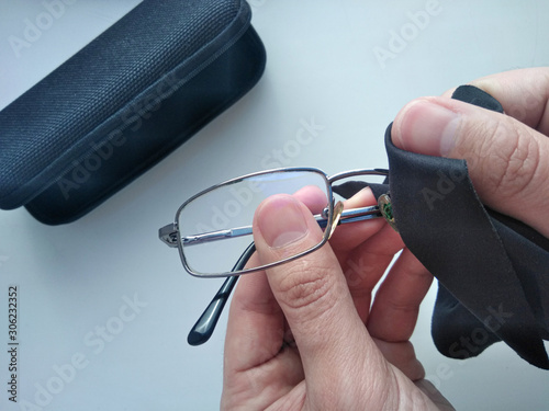 Black modern eyeglasses with case.Man wipes with a cloth the glass from contaminants.Cleaning glasses medical glasses.Glasses to restore vision.Glasses for the treatment of myopia and farsightedness.