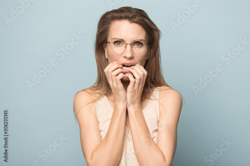 Nervous scared woman in glasses biting nails, feeling fear