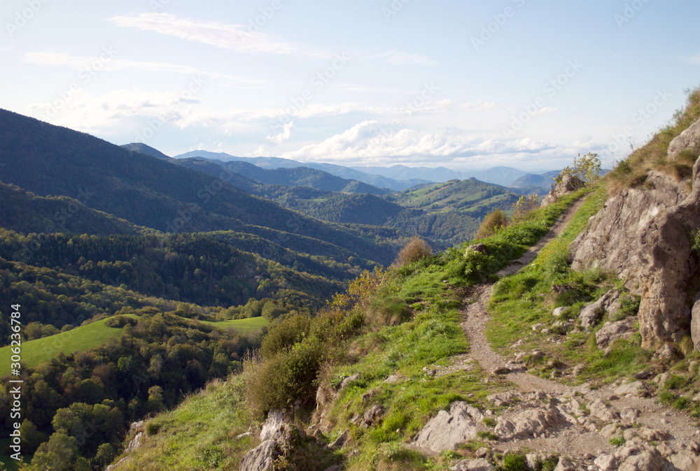 Naklejka premium Autumn landscape. An uphill path overlooking a beautiful hilly valley and blue cloudy skies in the South of France.