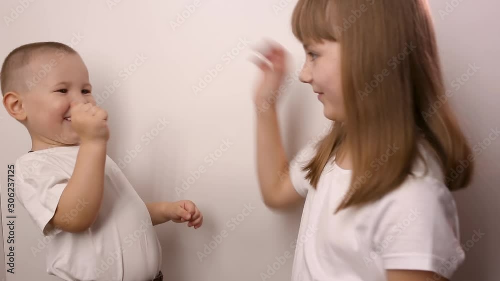 happy children wearing t-shirts play game rock paper scissor on white background, smile and laugh. boy and girl with playing together. little brother and elder sister have fun. small caucasian kids happy children wearing t-shirts play game rock paper scissor on white background, smile and laugh. boy and girl with playing together. little brother and elder sister have fun. small caucasian kids