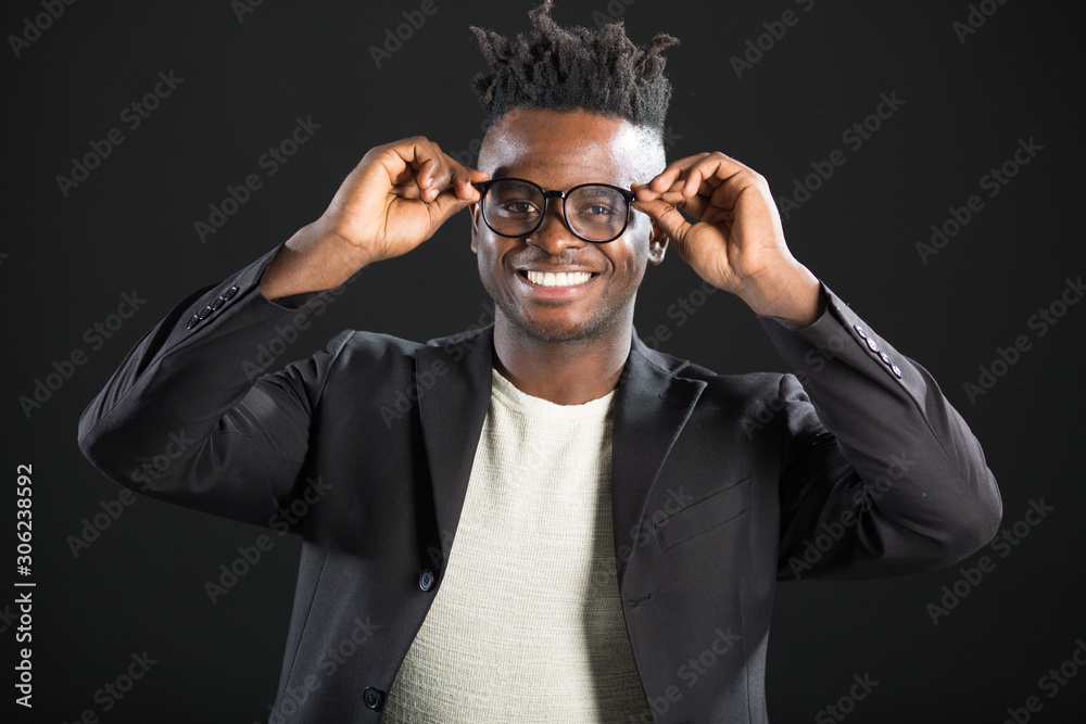 handsome African man in a suit with glasses on a black background