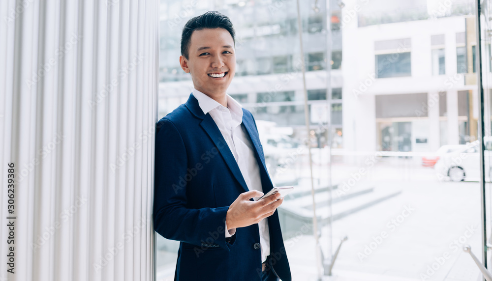Successful young modern Asian businessman using smartphone in downtown Successful young modern Asian businessman using smartphone in downtown
