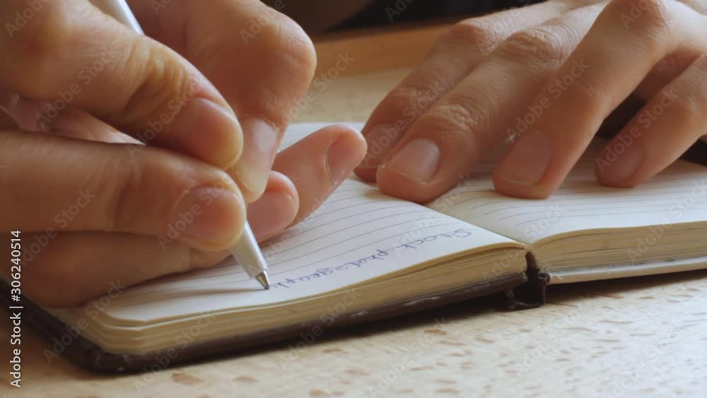 handwriting, writing diary in paper notebook, closeup of hand with pen