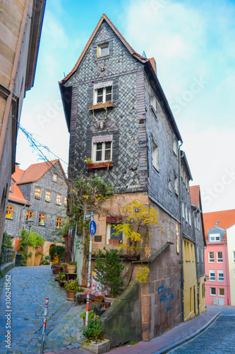 Furth  Germany  21 November 2019  street name Pfarrgasse. Narrow alley with tall artistically decorated dark houses. There are many flowers in the aisle. The houses are covered with dark tiles.
