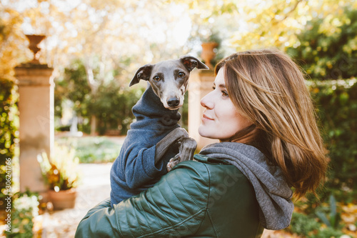 Foto Close-up of a beautiful young woman holding in her arms and hugging cute Italian Greyhound pup