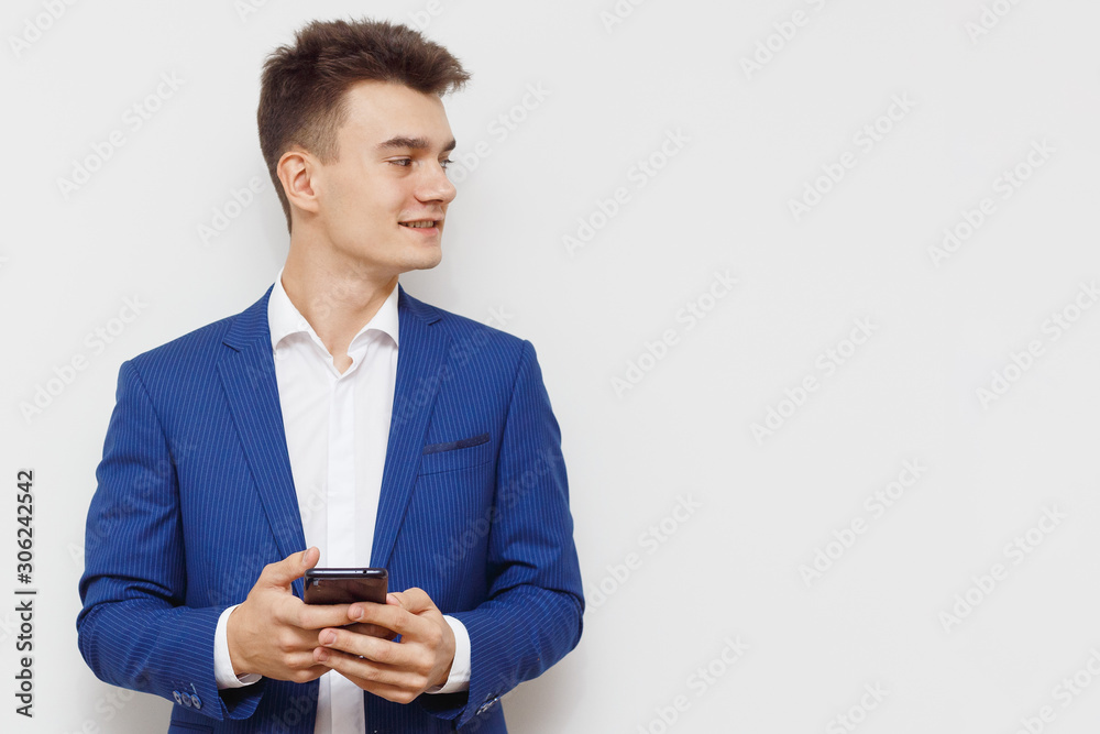 Young business man using his mobile device in business. Modern young guy with a phone in hand. Social networks business. Handsome man work on phone. Happy handsome guy browsing with his device. Young business man using his mobile device in business. Modern young guy with a phone in hand. Social networks business. Handsome man work on phone. Happy handsome guy browsing with his device.