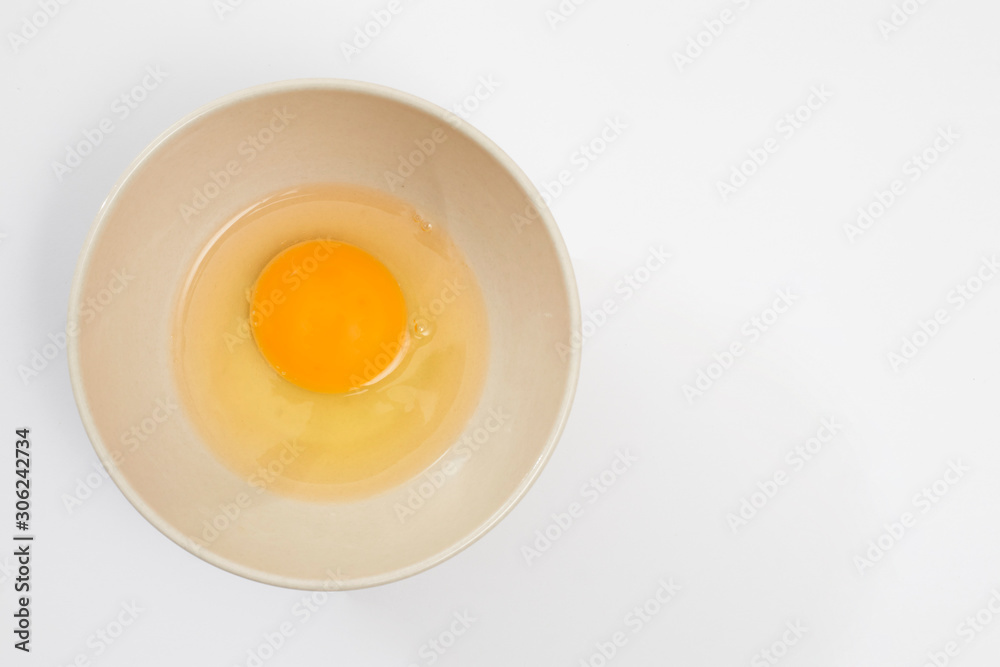 Broken egg in a beige bowl on white background Broken egg in a beige bowl on white background