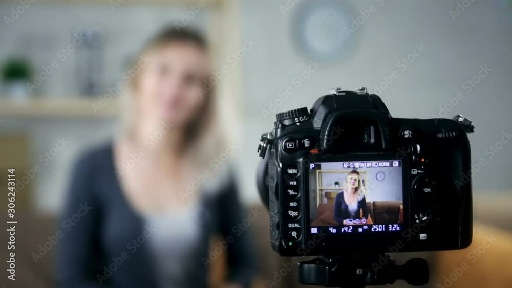 Young attractive woman blogger or vlogger looking at camera and talking on video shooting
