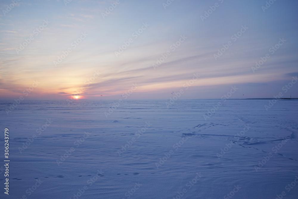 Snowy field and snow kiteboarders against the backdrop of a beautiful sunset.