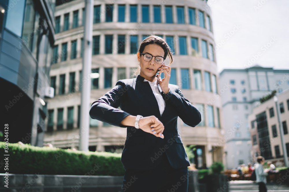Attractive confident female boss calling to employee for clarify time of meeting in business district, serious woman dressed in formal suit making important intern?tional call via app on cellular Attractive confident female boss calling to employee for clarify time of meeting in business district, serious woman dressed in formal suit making important intern?tional call via app on cellular