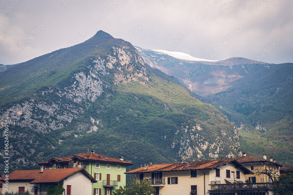 View of Italian town Arco, buildings and mountains. Snow on the top.