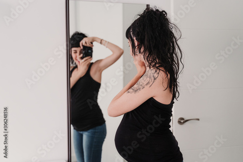 young pregnant woman at home taking a selfie on mirror with camera © Eva