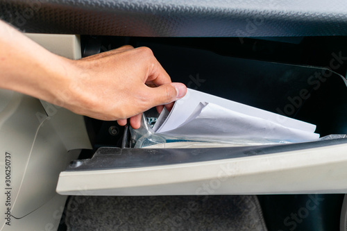 Φωτογραφία hand stirring papers in a glove box (dashboard)