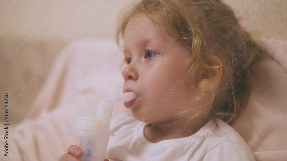 curly little girl undergoes procedure with inhaler to cure cold in soft bed with pillow in light room close view curly little girl undergoes procedure with inhaler to cure cold in soft bed with pillow in light room close view