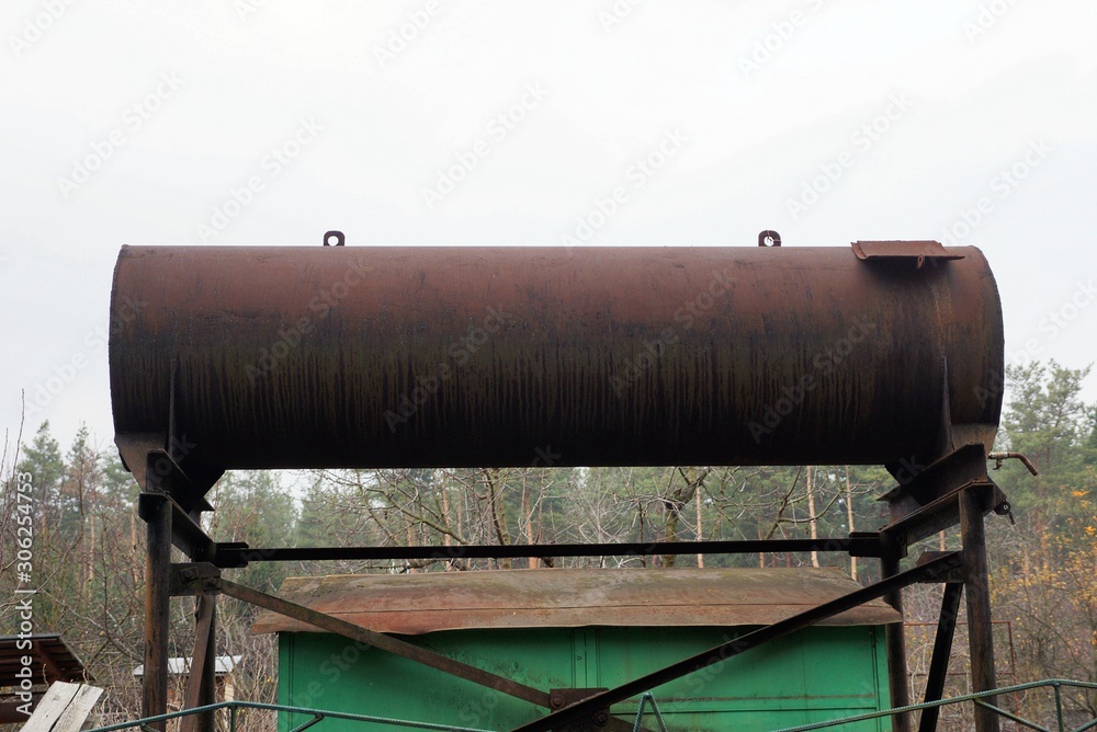 one brown rusty iron tank stands against a gray sky one brown rusty iron tank stands against a gray sky