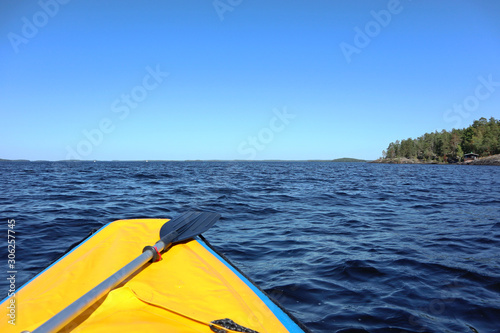 Rafting adventure first person view from yellow boat with paddle on finish lake bright sunny day blue water windy © Kathrine Andi