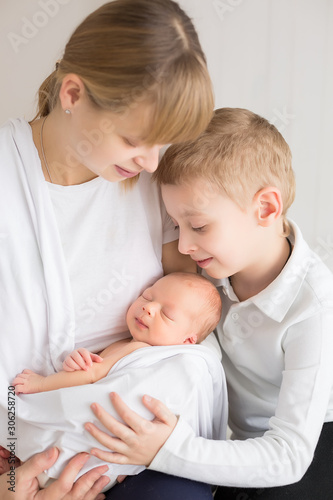 the mother holds the newborn in her arms, next to the eldest son. the first photo session of a newborn. Bros