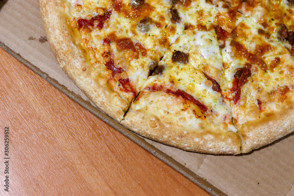 Meat pizza with cheese in a box on the table top view. Copy space. Italian pizza delivery concept Meat pizza with cheese in a box on the table top view. Copy space. Italian pizza delivery concept