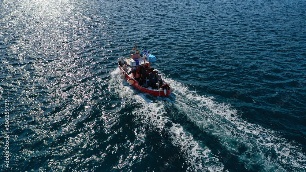 Obraz premium Aerial drone photo of traditional wooden fishing boat cruising in deep blue sea near port of Syros or Siros island, Cyclades, Greece