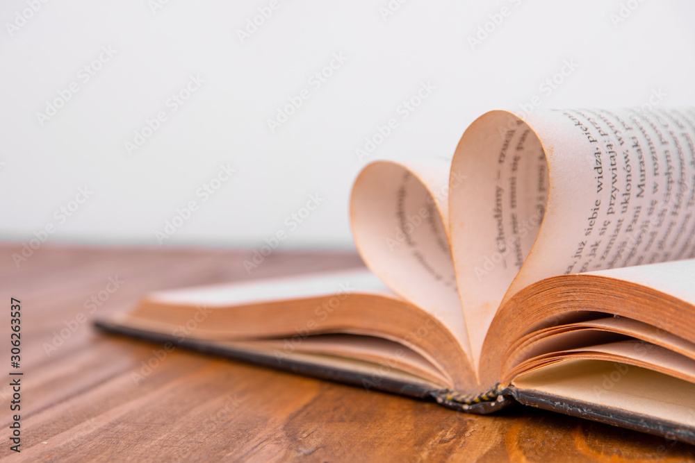 Fototapeta premium Old book and heart-shaped pages. White background. Wooden Table.