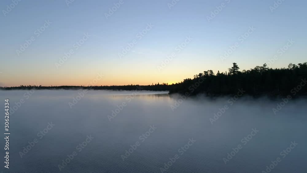 4K aerial descending flight over a fog covered lake on a misty fall morning in Northwest Ontario, Canada. 4K aerial descending flight over a fog covered lake on a misty fall morning in Northwest Ontario, Canada.